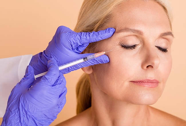 Close up photo middle aged woman undergo plastic surgery doctor make injection with syringe