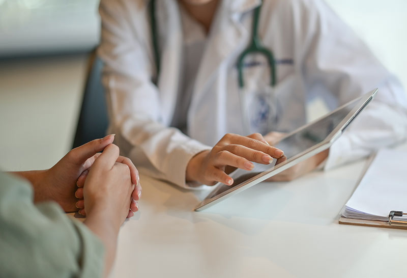 Doctor using tablet to discuss health with patient.